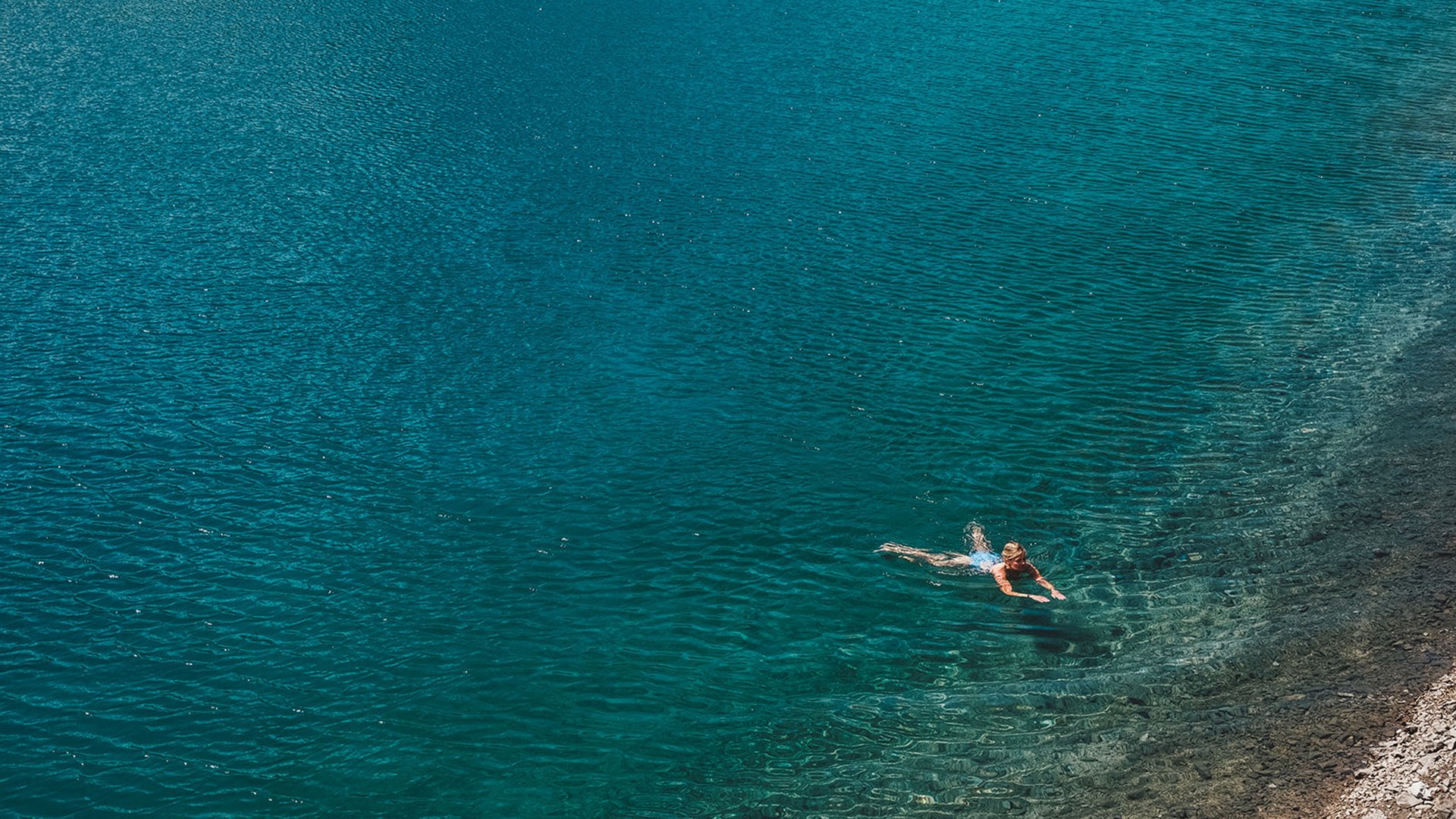 Aktivitäten in Lech für Jung und Alt Person schwimmt im klaren blauen Wasser nahe felsiger Küste